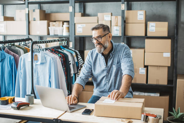 Mature man running online store Mature men at online shop. He is owner of small online shop. Receiving orders and packing boxes for delivery. labeling stock pictures, royalty-free photos & images