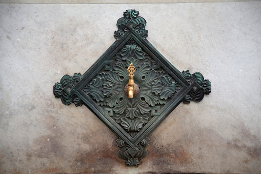 Old door knocker in the form of a circle on a green door