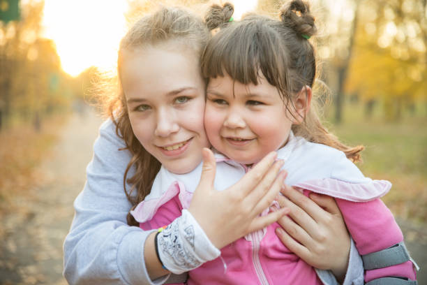 istock Two smiling sisters in warm clothes spending time in autumn park 1281476736