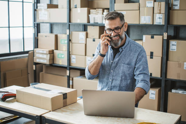 Mature man running online store Mature men at online shop. He is owner of small online shop. Receiving orders and packing boxes for delivery. market vendor stock pictures, royalty-free photos & images