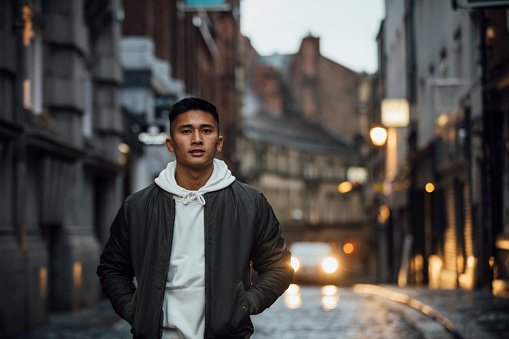 A front view of a young man walking down a street outdoors in Newcastle upon Tyne city centre.