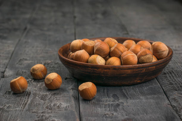 istock Ripe hazelnuts in a clay bowl on a black wooden table. 1281477257
