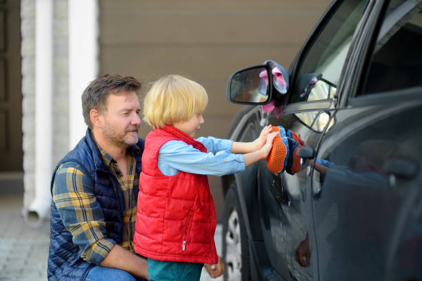 父親が家族の車を洗うのを手伝う未就学児。小さなお父さんのヘルパー。子供を持つ家族は一緒に時間を過ごす - 11244 ストックフォトと画像