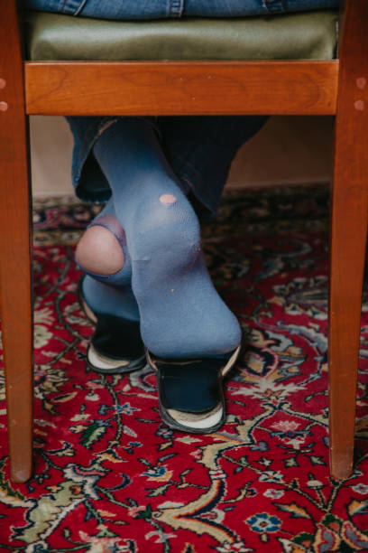 istock Man sits on chair on his socks can see holes 1281478567