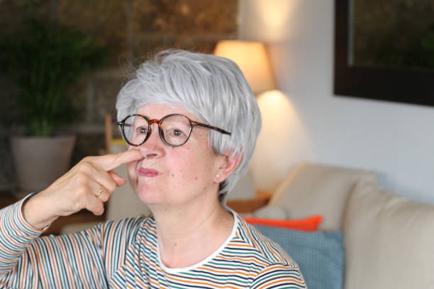 mujer mayor recogiendo su nariz en casa - picking nose fotografías e imágenes de stock