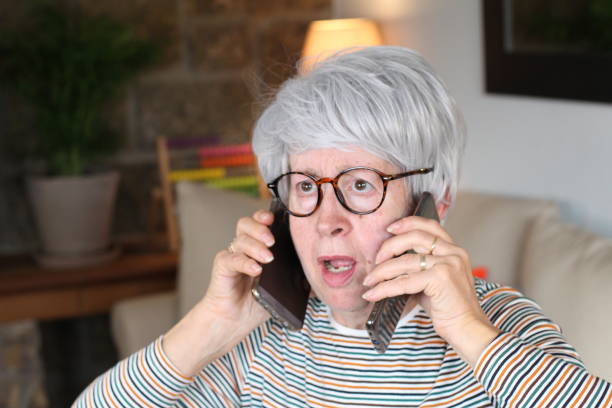 istock Senior overwhelmed woman using two cellphones 1281480050