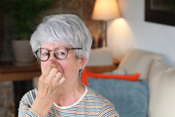 senior woman blocking nose from unpleasant smell - facial expression unpleasant smell shirt caucasian imagens e fotografias de stock