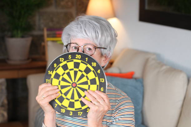 scared senior woman holding bulls eye - bulls eye dart target dartboard imagens e fotografias de stock