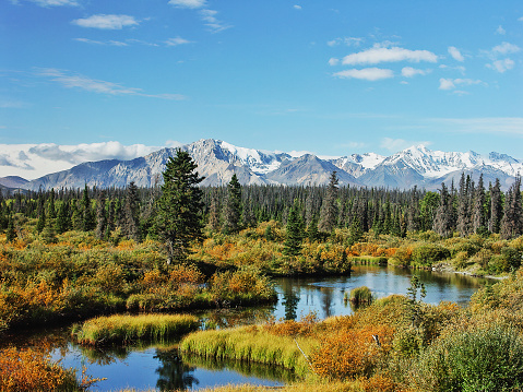 Long mountain range surrounded by vast ice sheet rising above sea; even bigger mountains in background