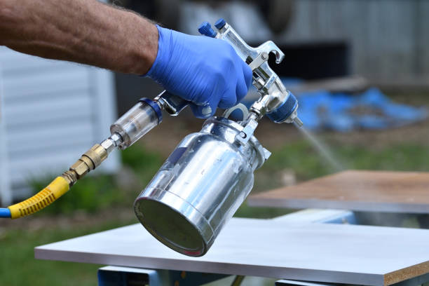 Handyman Spraying Paint Using a Spray Gun Outside in Backyard