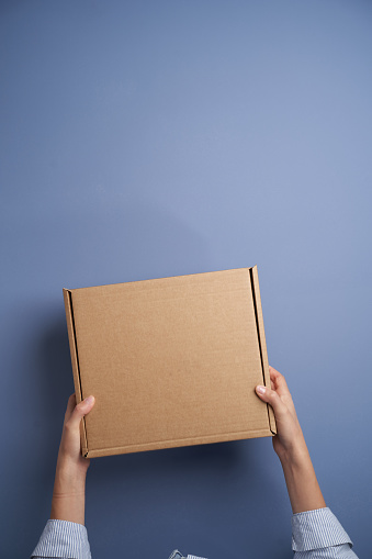 Woman hands open empty cardboard box, top view. Female hands holding gift or present box. Parcel delivery