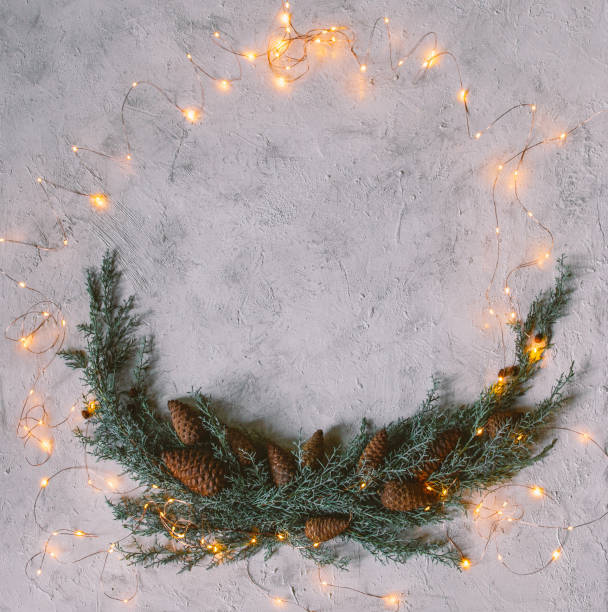 istock Creative frame of Christmas tree branches and spruce cone with warm light. 1281489583