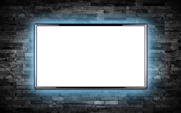 istock empty black flat tv screen display with copy space isolated white background. television wall mounted  dark slate stone wall glowing blue LED background. Multimedia streaming internet cloud concept 1281490737