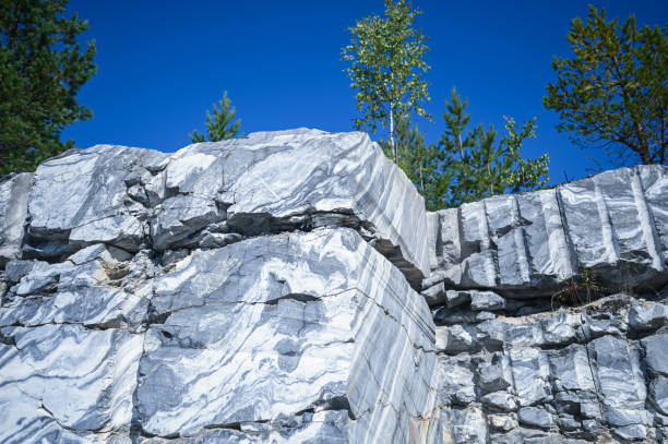 roche coupée surface brute de marbre blanc et gris dans l’environnement naturel. texture de carrière de marbre bleu - rock quarry photos et images de collection