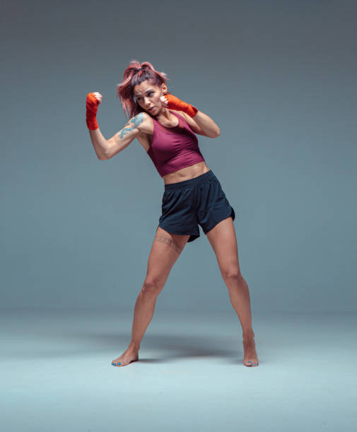 combattente femminile si allena in bende di boxe in studio su sfondo grigio. - undercutting foto e immagini stock