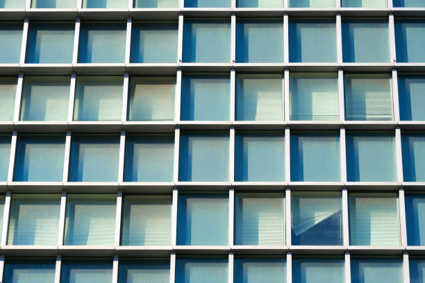 detalhe da fachada de construção com um padrão de grade de janelas com mullions profundos em uma cor verde pálida e azul, pegando a cor do céu - mullions - fotografias e filmes do acervo