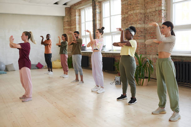 Dance class in studio Group of young people standing and repeating the movements of the instructor in exercise class dance studio instructor stock pictures, royalty-free photos & images