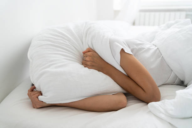 istock Depressed woman lying alone on bed covering head with pillow feeling afraid or depressed suffer from insomnia, loud sounds of neighbors, has mental problems after divorcing her husband 1281497257
