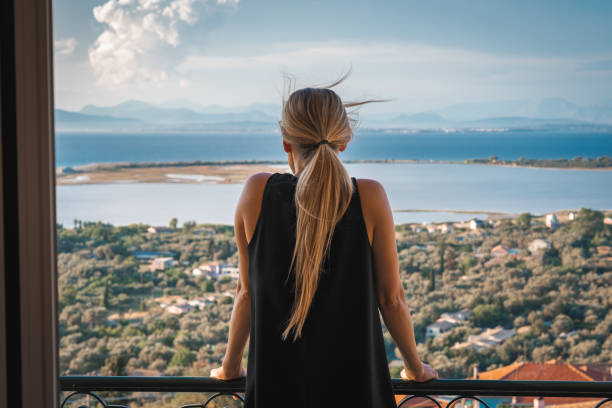 istock Young woman enjoys seaside viewpoint from balcony 1281498083