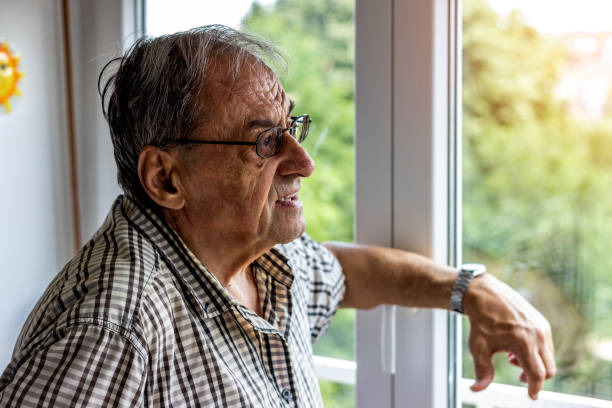 istock Elderly man looking outside the window. 1281499623