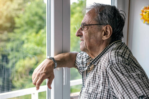 istock Elderly man looking outside the window. 1281499630