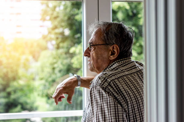 un hombre mayor en casa. - pensive senior adult looking through window indoors fotografías e imágenes de stock