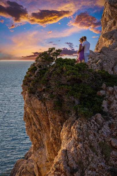 istock Young couple enjoying a beautiful sunset on the cliff, Cape Lefkas, Lefkada 1281500266
