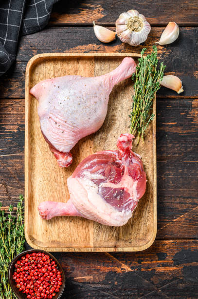 istock Raw Duck legs on a wooden tray.  Dark background. Top view 1281503485