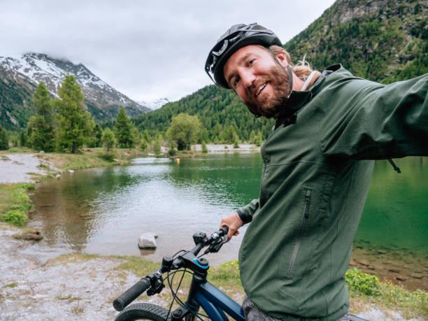 istock Young man mountain biker on trail takes selfie 1281504183