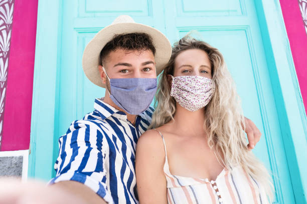 istock Young couple in vacation taking a selfie while wearing protective face mask for coronavirus 1281504686