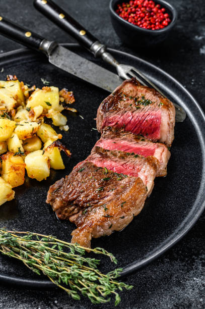 bistecca alla griglia con patate, carne di manzo. sfondo nero. vista dall'alto - steak strip steak prepared potato grilled foto e immagini stock