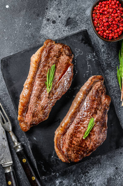 istock Grilled ramp cap steak on a stone chopping Board. Black background. Top view 1281504962