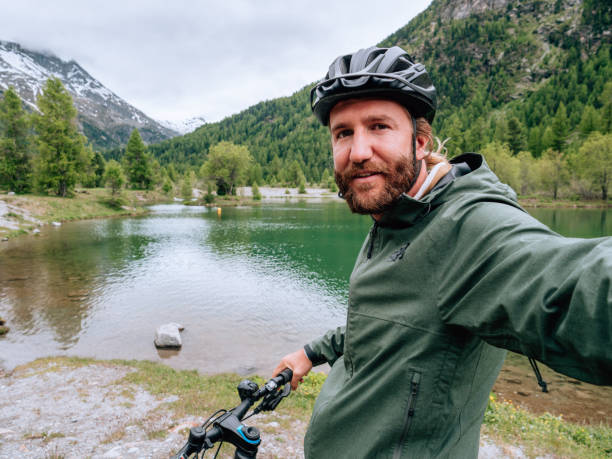 istock Young man mountain biker on trail takes selfie 1281505003
