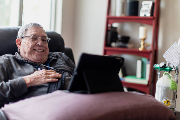 Senior man relaxing and having a good time while sitting in a recliner and watching funny content on his tablet.