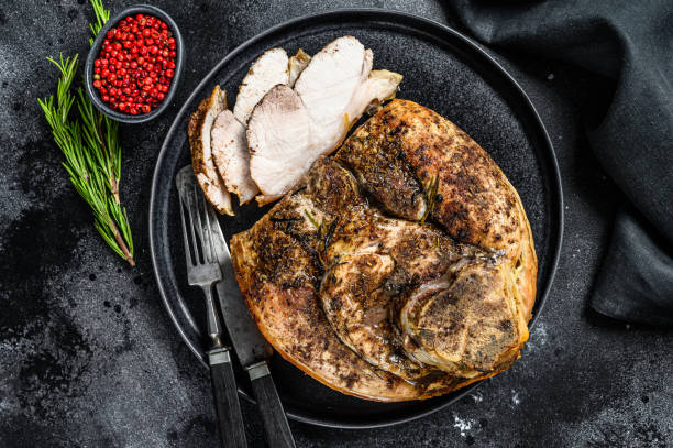 istock Roast sliced pork knuckle on a plate. Leg meat.  Black background. Top view 1281507007