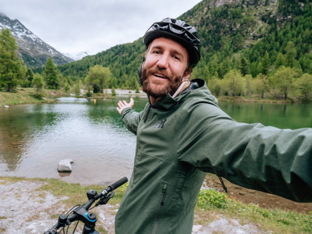 istock Young man mountain biker on trail takes selfie 1281507137