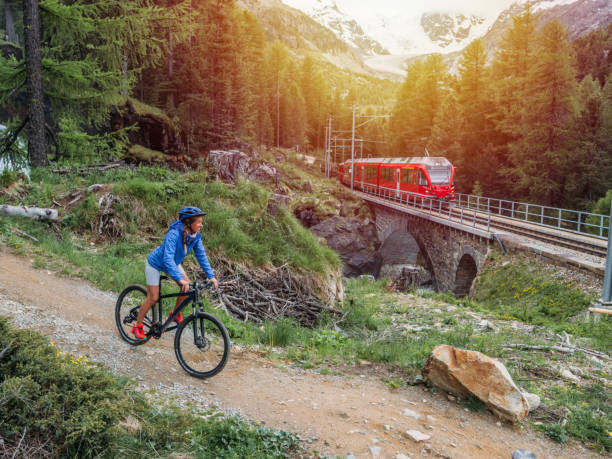 Mountain biker on flow trail, Switzerland Woman on mountain bike passing on flow trail near Swiss train graubunden canton stock pictures, royalty-free photos & images