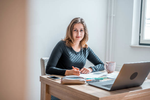 istock Caucasian Female Student Learning At Home Using Laptop And Looking At Camera 1281507713