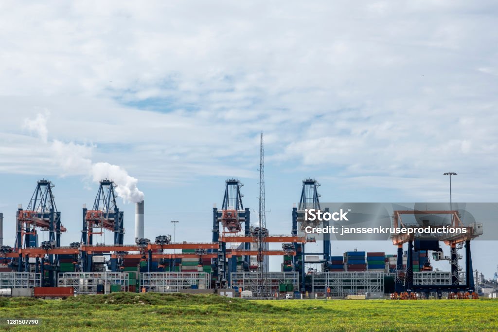 ROTTERDAM, THE NETHERLANDS Container being loaded by gantry cranes in the Maasvlakte in the Port of Rotterdam ROTTERDAM, THE NETHERLANDS Container being loaded by gantry cranes in the Maasvlakte in the Port of Rotterdam. Blue Stock Photo