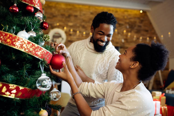 istock Happy black couple talking while decorating Christmas tree at home. 1281507814