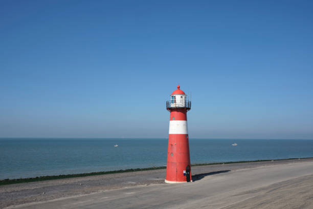 istock Red and white lighthouse on a blue sky background, Westkapelle in The Netherlands 1281508435