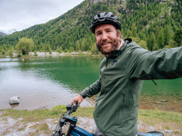 istock Young man mountain biker on trail takes selfie 1281508611
