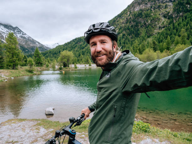 istock Young man mountain biker on trail takes selfie 1281508820