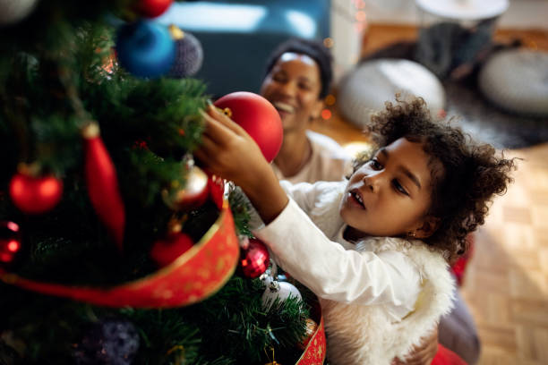 istock Small black girl decorating Christmas tree at home. 1281508900