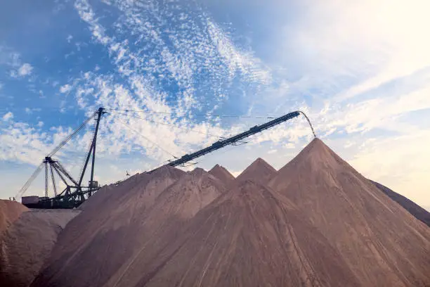 Photo of Extracting and mining potassium salts. Large excavator machine and Huge mountains of waste ore in the extraction of potassium against the backdrop of sky.