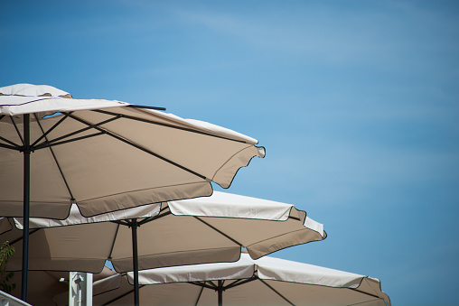 closeup of beige umbrellas alignment on blue sky background