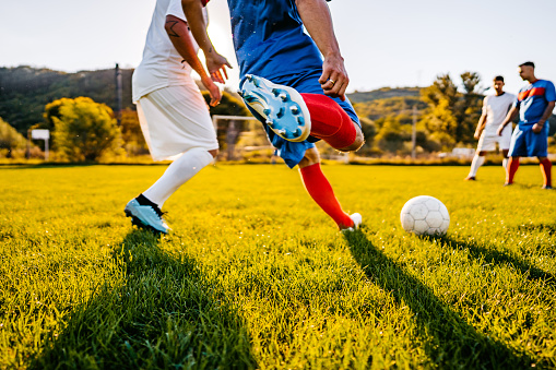 Soccer players playing football at sunset.