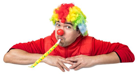 Full length portrait of a mime posing with crossed arms in front of clowns isolated on white background