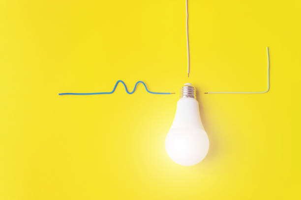 istock White glowing light bulb Against Yellow Background with wires phase, zero, ground. Idea, innovation, creativity concept, design template. Power energy economy concept. 1281513964