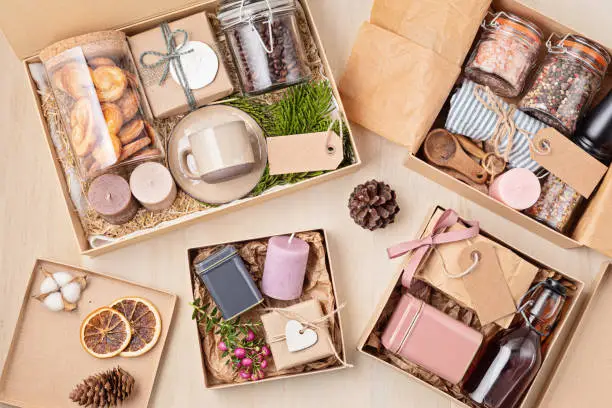 Photo of Preparing care package, seasonal gift box with coffee, cookies, candles, spices and cups